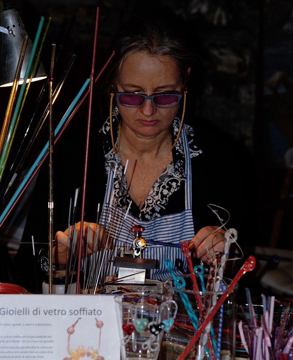 artisan working on glass jewels, photographed in low-light